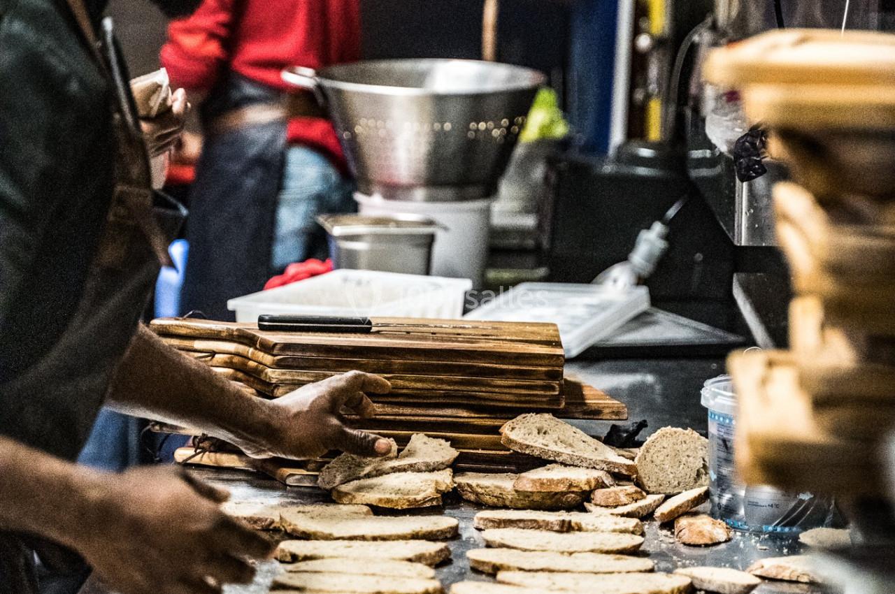 Un cuisinier dispose des tranches de pain sur un plan de travail dans une cuisine professionnelle.