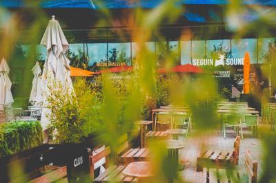 Miniature Location salle Boulogne-Billancourt (Hauts-de-Seine) - Seguin Sound #37 Terrasse extérieure d'un restaurant avec tables, chaises, parasols et végétation, vue à travers des feuillages.