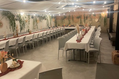 Deux grands arbres bordent une pelouse verdoyante sous un ciel partiellement nuageux.