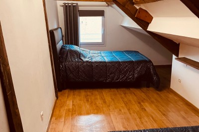 Deux grands arbres bordent une pelouse verdoyante sous un ciel partiellement nuageux.