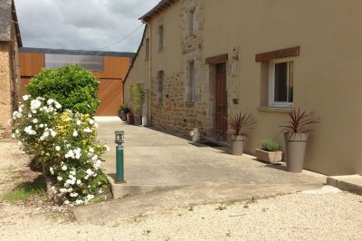 Deux grands arbres bordent une pelouse verdoyante sous un ciel partiellement nuageux.