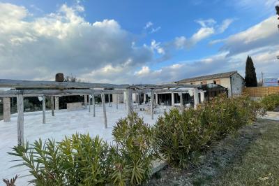 Salle rustique avec murs en pierre, tonneaux en bois servant de tables, tabourets métalliques et éclairage chaleureux.