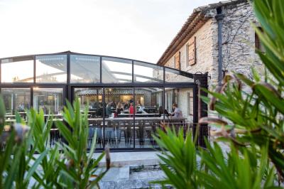 Salle rustique avec murs en pierre, tonneaux en bois servant de tables, tabourets métalliques et éclairage chaleureux.