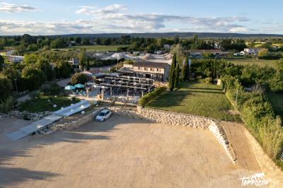 Salle rustique avec murs en pierre, tonneaux en bois servant de tables, tabourets métalliques et éclairage chaleureux.
