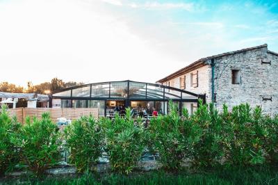Salle rustique avec murs en pierre, tonneaux en bois servant de tables, tabourets métalliques et éclairage chaleureux.