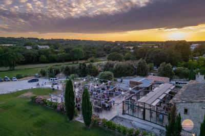 Salle rustique avec murs en pierre, tonneaux en bois servant de tables, tabourets métalliques et éclairage chaleureux.