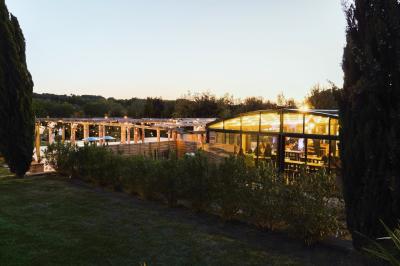 Salle rustique avec murs en pierre, tonneaux en bois servant de tables, tabourets métalliques et éclairage chaleureux.
