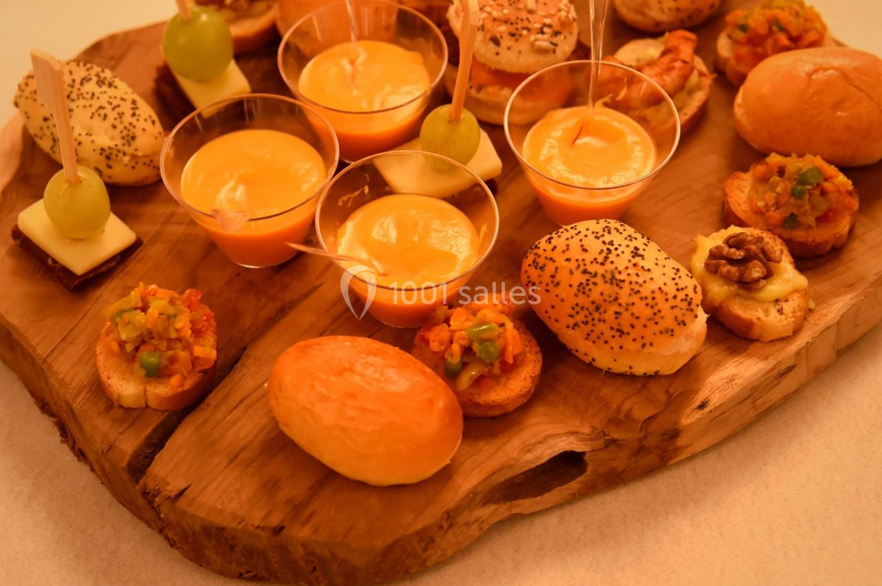 Plateau en bois garni de bouchées salées variées, mini-pains, verrines et amuse-bouches décorés.
