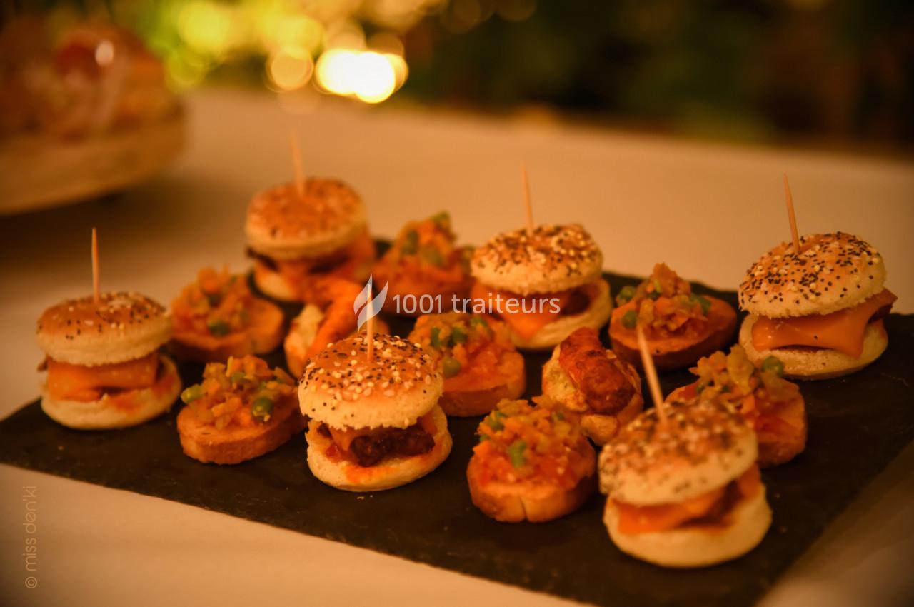 Plateau de mini-burgers et bouchées garnies de légumes, présenté sur une ardoise dans un cadre chaleureux.