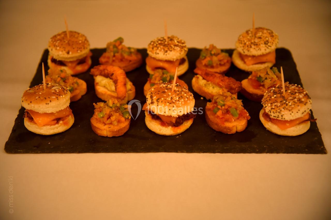 Plateau de mini-burgers et bouchées garnies de légumes et crevettes, disposés sur une ardoise noire.