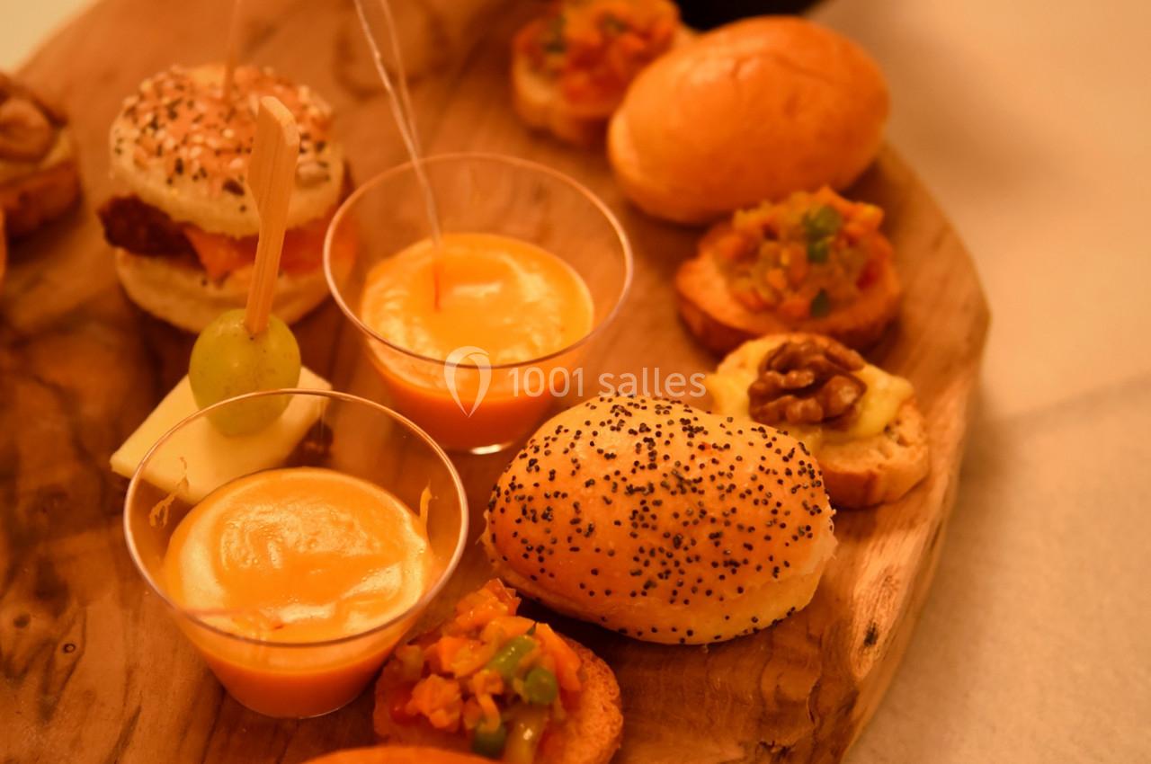 Plateau en bois avec assortiments de bouchées salées, verrines et pains garnis, accompagné de couverts en bois.