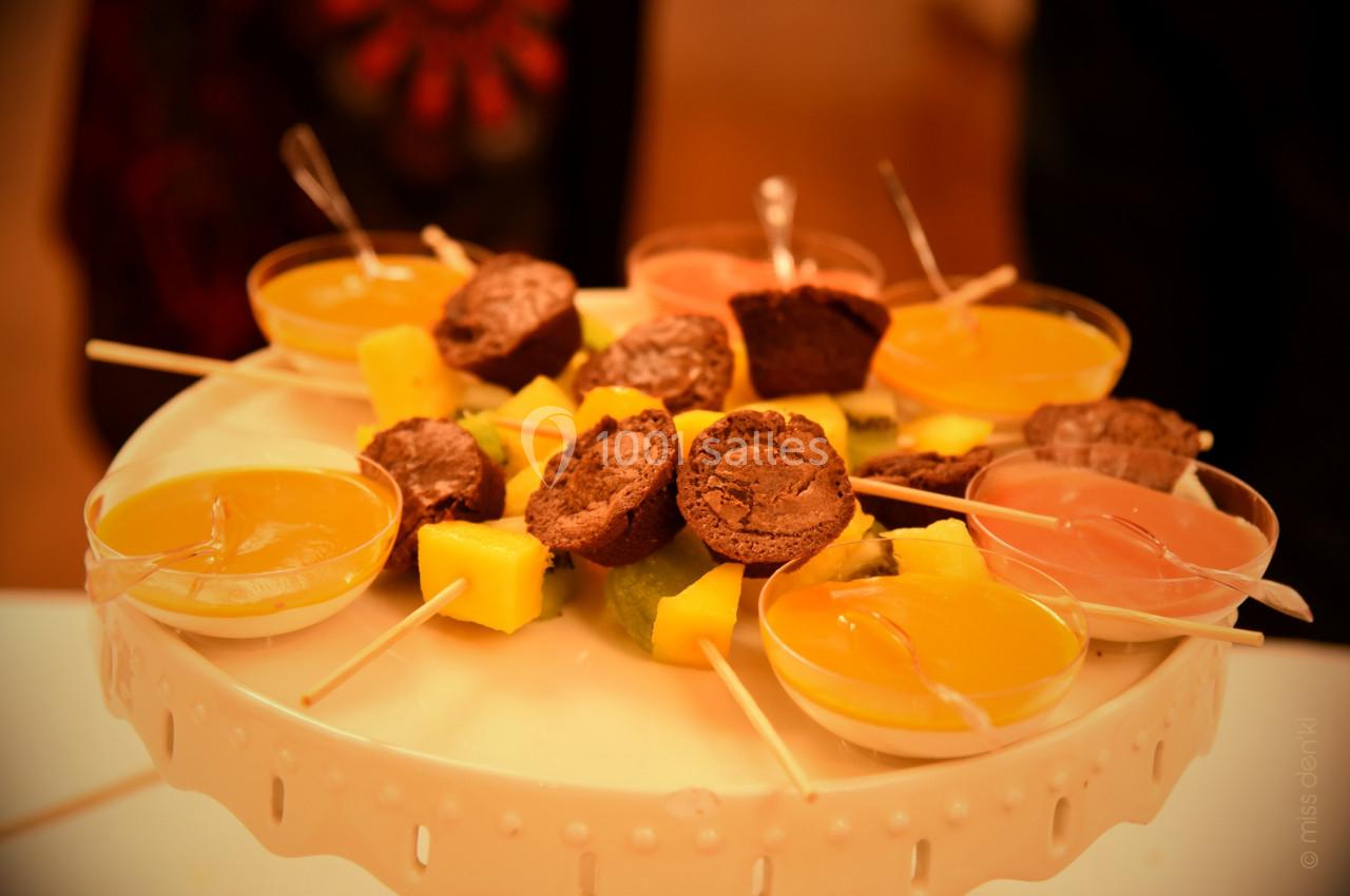 Plateau de desserts avec verrines colorées, morceaux de fruits et mini-gâteaux au chocolat sur des bâtonnets.
