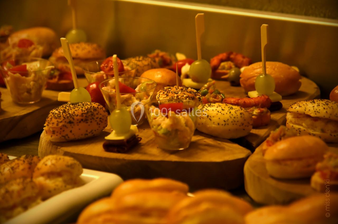 Plateau de bouchées apéritives variées, incluant mini-burgers, verrines et brochettes, disposées sur des planches en bois.
