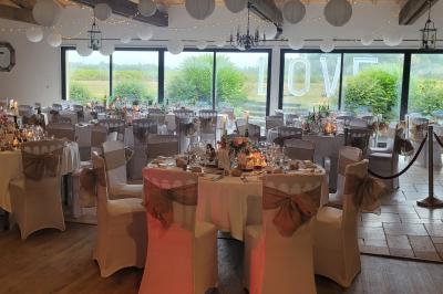 Rangées de tonneaux en bois alignés dans une cave voûtée avec éclairage tamisé.