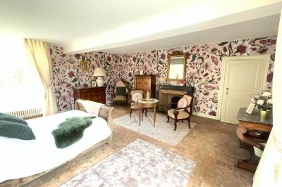 Rangées de tonneaux en bois alignés dans une cave voûtée avec éclairage tamisé.