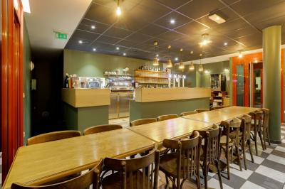 Table ronde dressée avec des verres, couverts et un centre de table en épis de blé dans un restaurant au sol carrelé.