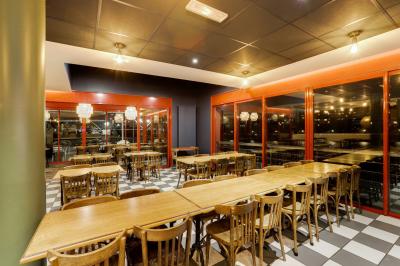 Table ronde dressée avec des verres, couverts et un centre de table en épis de blé dans un restaurant au sol carrelé.