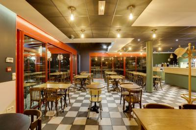 Table ronde dressée avec des verres, couverts et un centre de table en épis de blé dans un restaurant au sol carrelé.