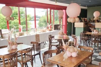 Table ronde dressée avec des verres, couverts et un centre de table en épis de blé dans un restaurant au sol carrelé.
