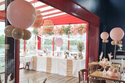 Table ronde dressée avec des verres, couverts et un centre de table en épis de blé dans un restaurant au sol carrelé.