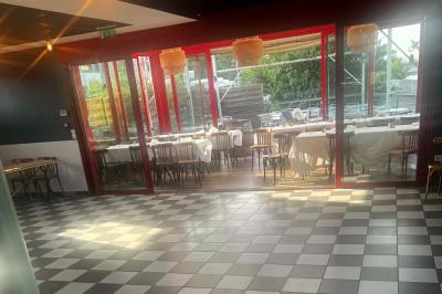 Table ronde dressée avec des verres, couverts et un centre de table en épis de blé dans un restaurant au sol carrelé.