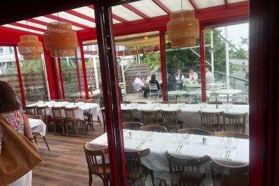 Table ronde dressée avec des verres, couverts et un centre de table en épis de blé dans un restaurant au sol carrelé.