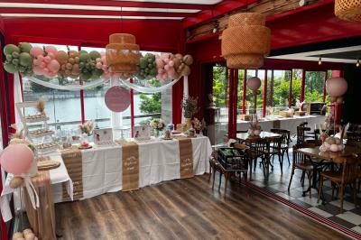 Table ronde dressée avec des verres, couverts et un centre de table en épis de blé dans un restaurant au sol carrelé.