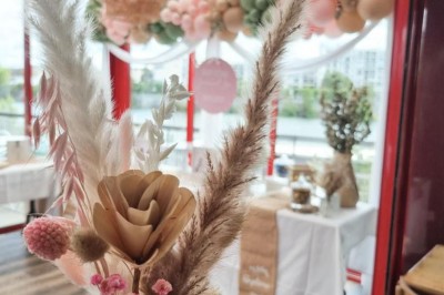 Terrasse extérieure avec tables, chaises en osier, tonneau en bois et vue sur un fleuve bordé de végétation.