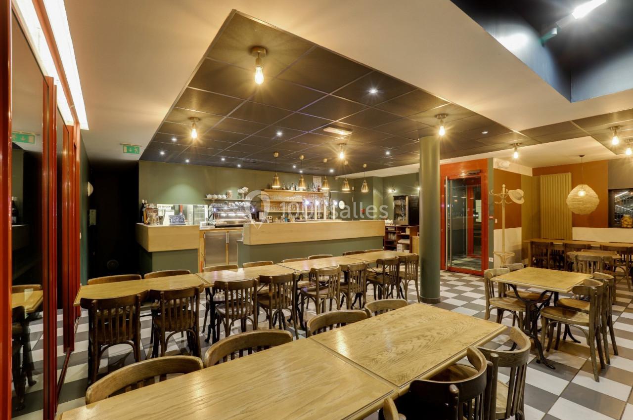 Salle de restaurant lumineuse avec tables en bois, chaises assorties et comptoir en arrière-plan.