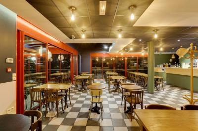 Terrasse extérieure avec tables et chaises en métal, éclairée la nuit, protégée par des toiles tendues.