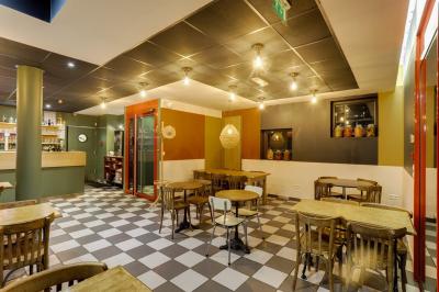 Terrasse extérieure avec tables et chaises en métal, éclairée la nuit, protégée par des toiles tendues.