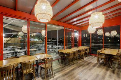 Terrasse extérieure avec tables et chaises en métal, éclairée la nuit, protégée par des toiles tendues.