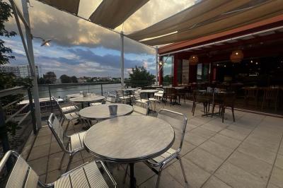 Terrasse extérieure avec tables et chaises en métal, éclairée la nuit, protégée par des toiles tendues.