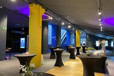 Espace intérieur avec tables hautes noires, distributeur automatique et éclairage tamisé dans un cadre moderne.