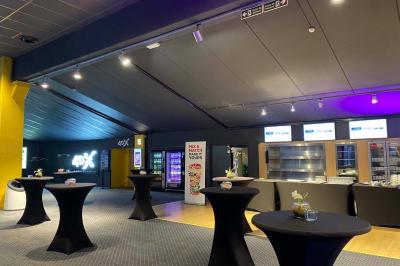 Espace intérieur avec tables hautes noires, distributeur automatique et éclairage tamisé dans un cadre moderne.