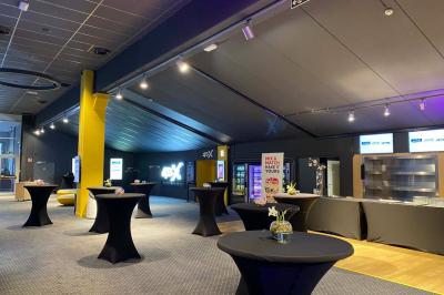 Espace intérieur avec tables hautes noires, distributeur automatique et éclairage tamisé dans un cadre moderne.