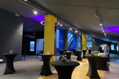 Espace intérieur avec tables hautes noires, distributeur automatique et éclairage tamisé dans un cadre moderne.