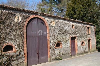 Chambre lumineuse avec lit double, fauteuils, cheminée, meubles anciens et mur décoré de motifs floraux.