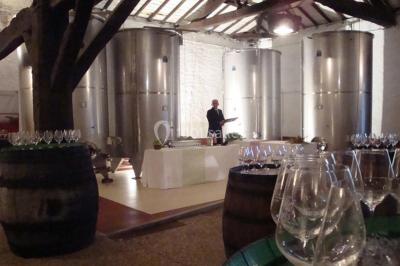 Chambre lumineuse avec lit double, fauteuils, cheminée, meubles anciens et mur décoré de motifs floraux.