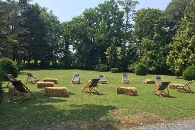 Chambre lumineuse avec lit double, fauteuils, cheminée, meubles anciens et mur décoré de motifs floraux.