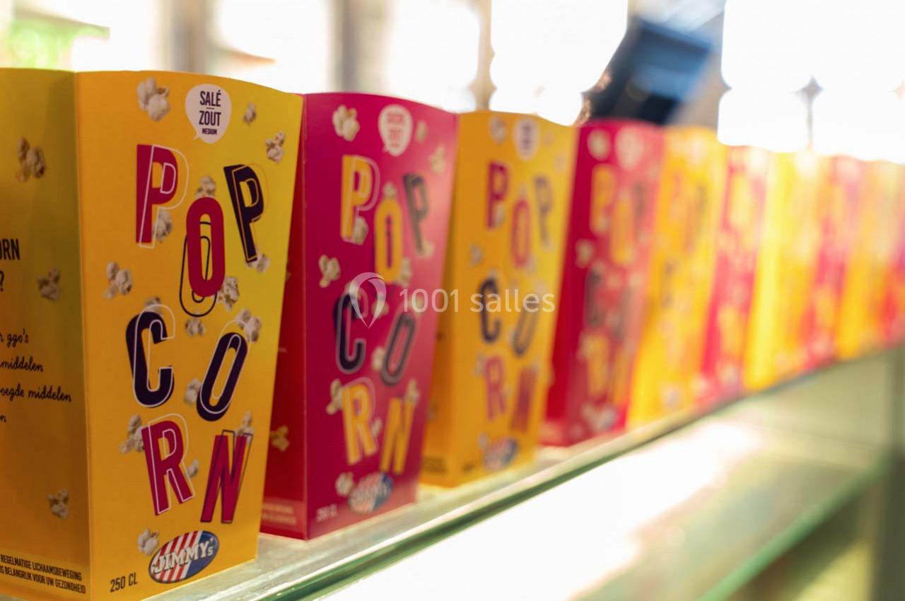 Boîtes de pop-corn colorées alignées sur une étagère en verre dans un environnement lumineux.