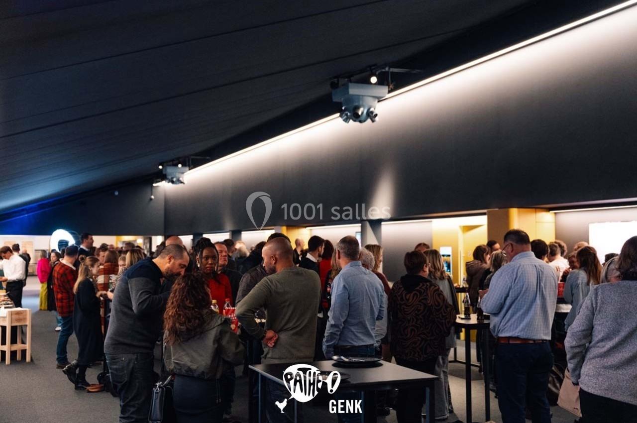 Groupe de personnes discutant debout dans un espace intérieur éclairé, ambiance conviviale.