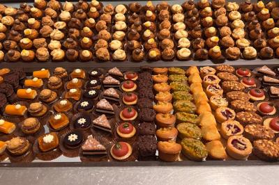 Lit double avec draps blancs, couverture bleue et coussins décoratifs, encadré par deux lampes murales allumées.