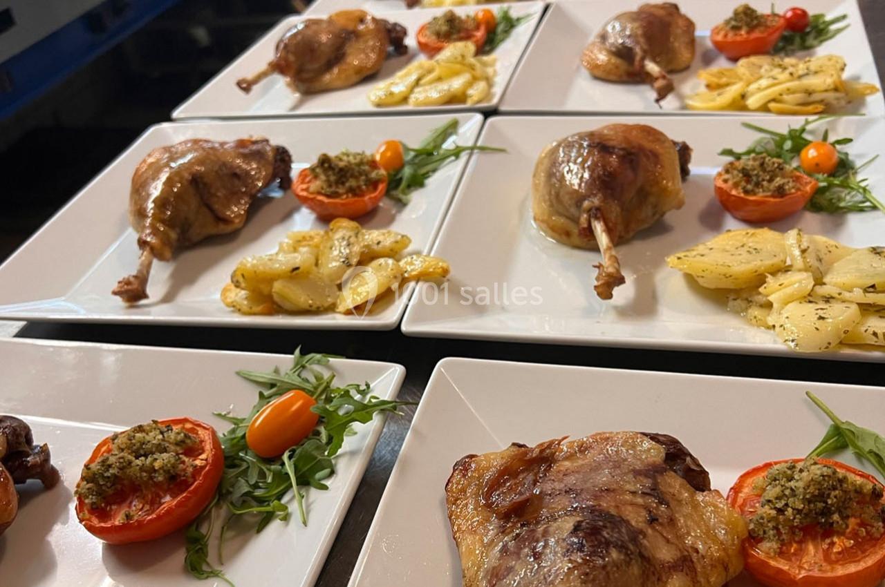 Assiettes dressées avec cuisses de canard confites, pommes de terre, tomates farcies et roquette.