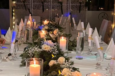 Lit double avec draps blancs, couverture bleue et coussins décoratifs, encadré par deux lampes murales allumées.