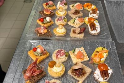 Lit double avec draps blancs, couverture bleue et coussins décoratifs, encadré par deux lampes murales allumées.