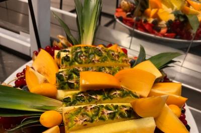 Lit double avec draps blancs, couverture bleue et coussins décoratifs, encadré par deux lampes murales allumées.