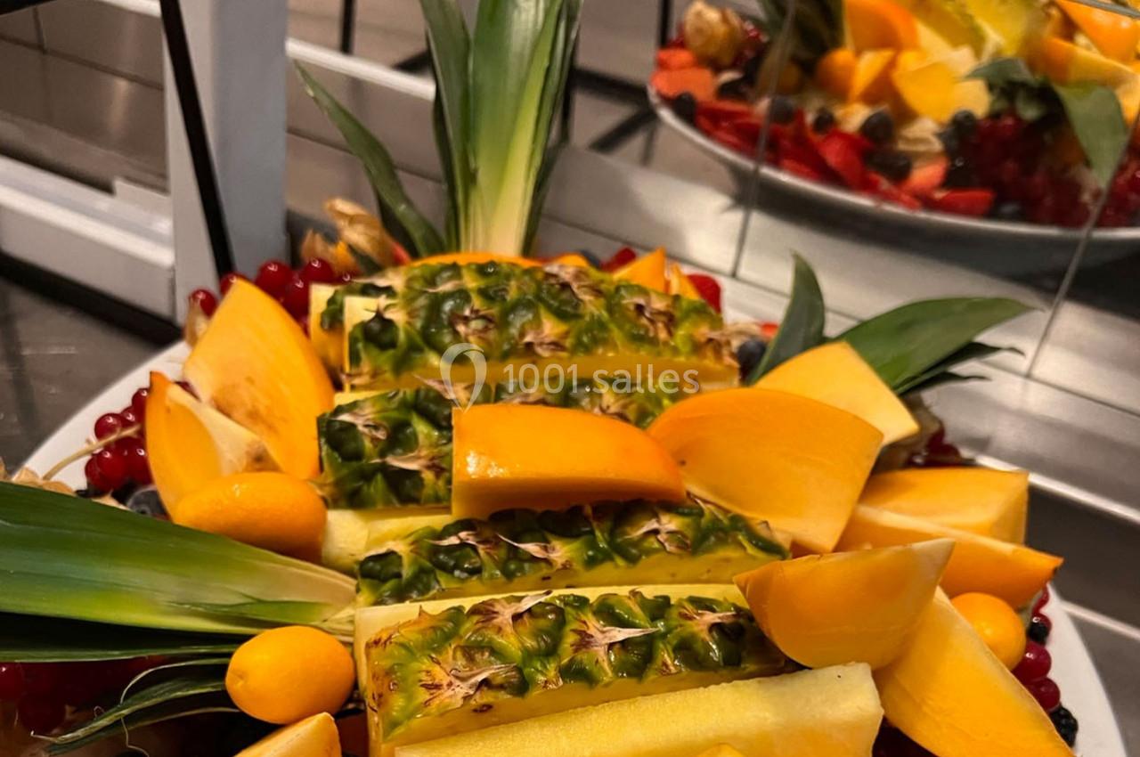 Assortiment de fruits frais comprenant ananas, kakis, groseilles et autres fruits colorés disposés sur un plateau.