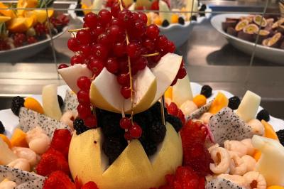 Lit double avec draps blancs, couverture bleue et coussins décoratifs, encadré par deux lampes murales allumées.