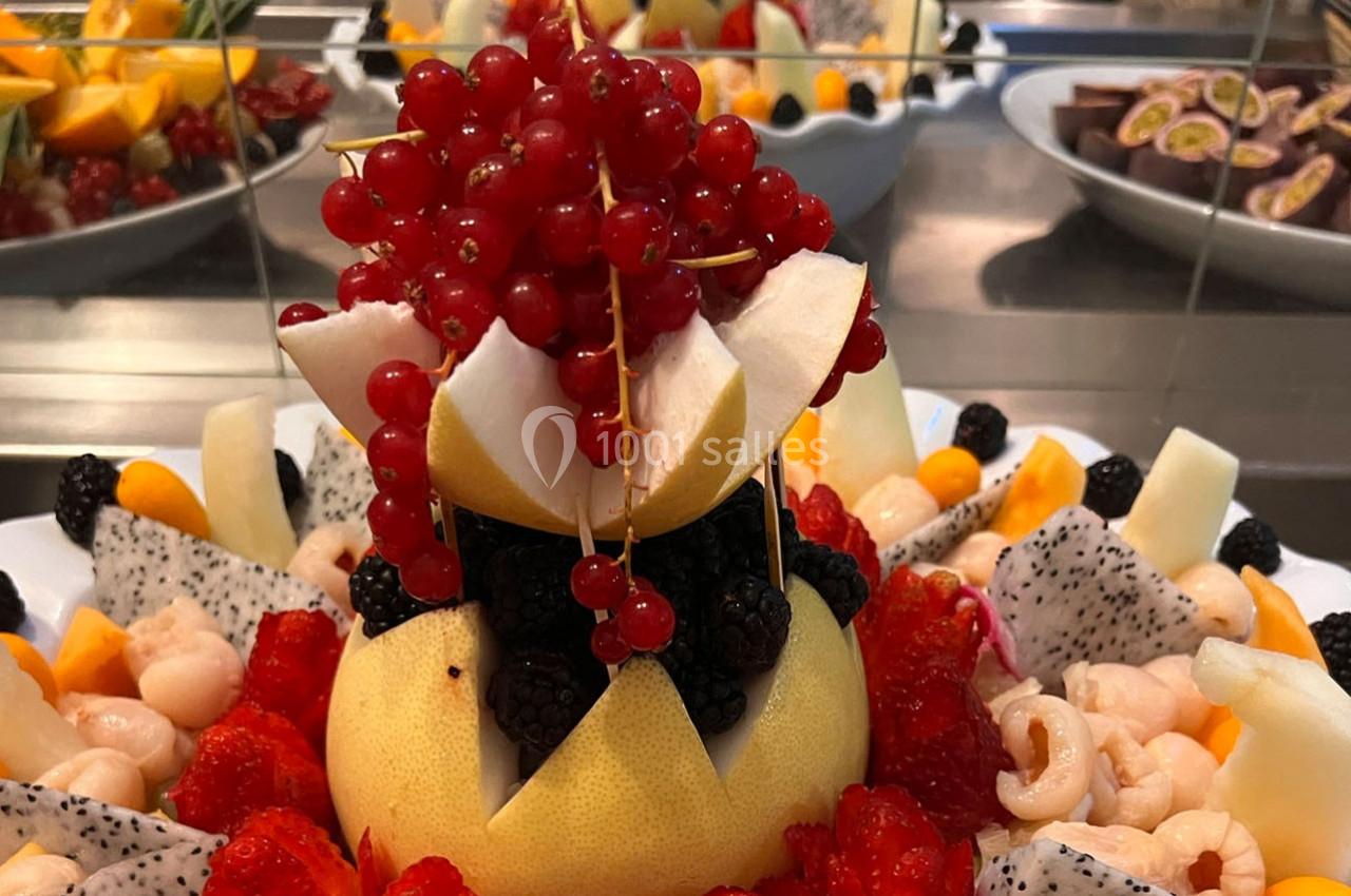 Assiette garnie de fruits variés, avec un pamplemousse décoré au centre entouré de baies, litchis et tranches exotiques.